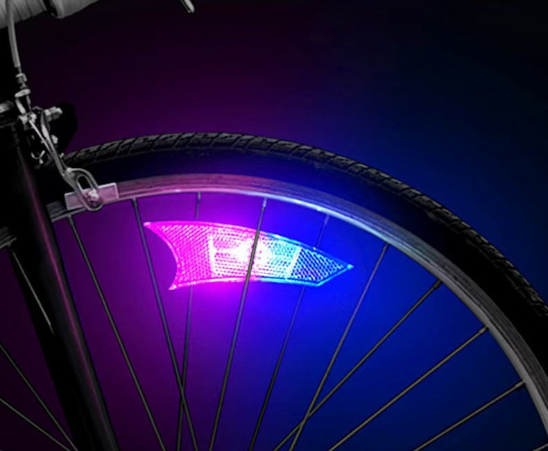 Pink-and-blue spoke light installed on a bicycle wheel at night
